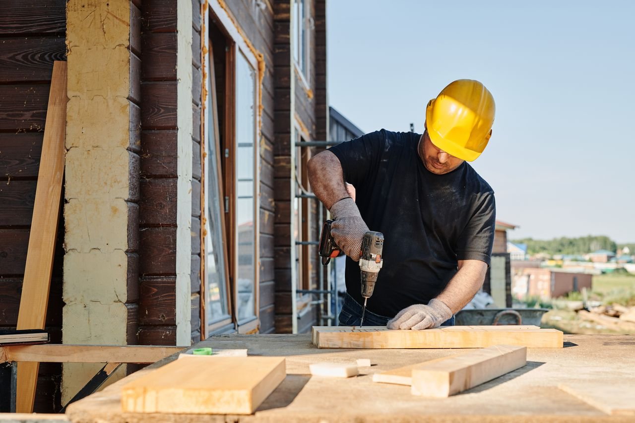 Free A construction worker using a power drill on a building site, outdoors during the day. Stock Photo